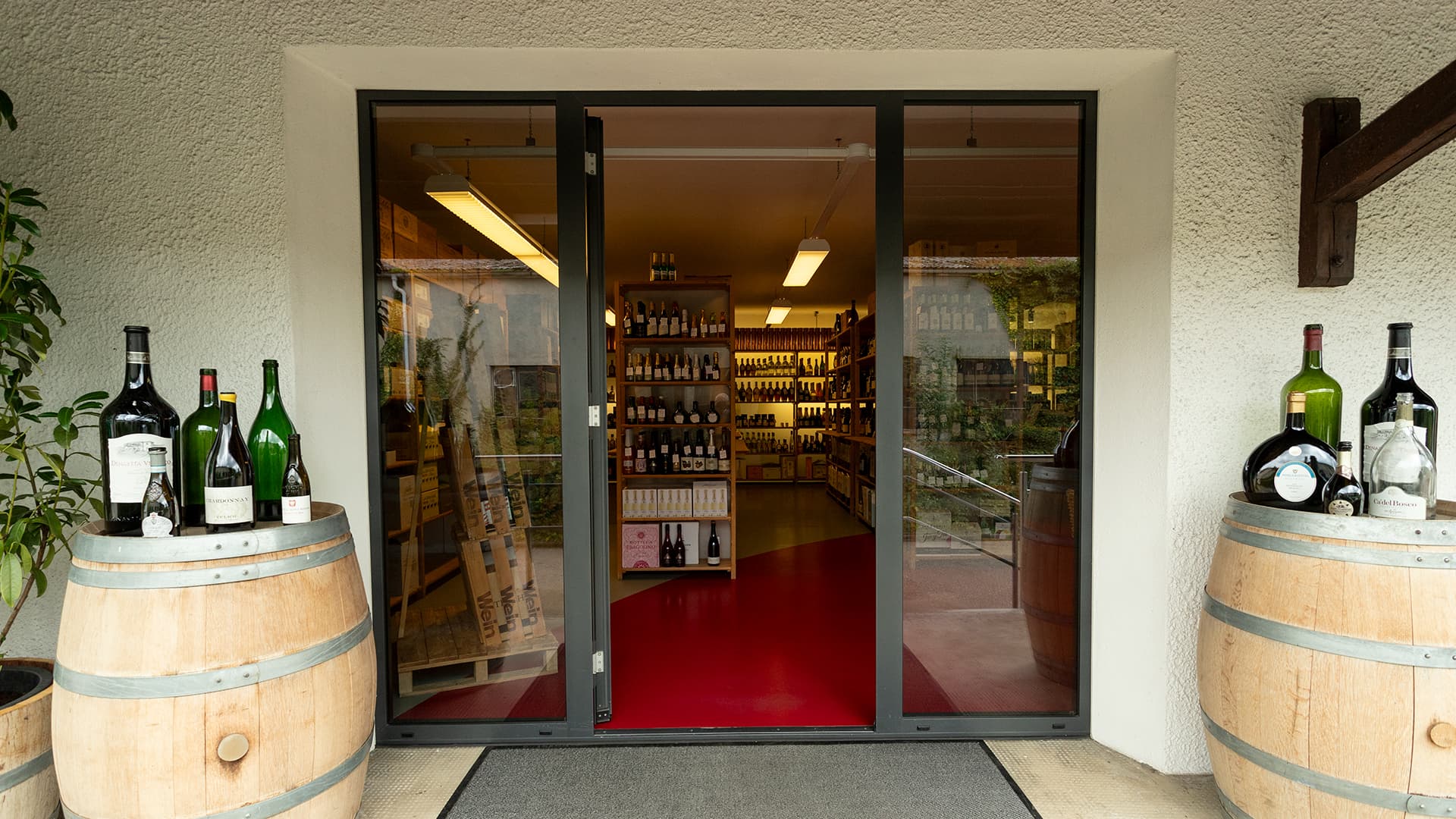 Der Eingangsbereich von Wein-Engelhardt. Die offene Tür gewährt einen Blick ins Ladengeschäft auf die vollen Wein- und Spirituosenregale.
